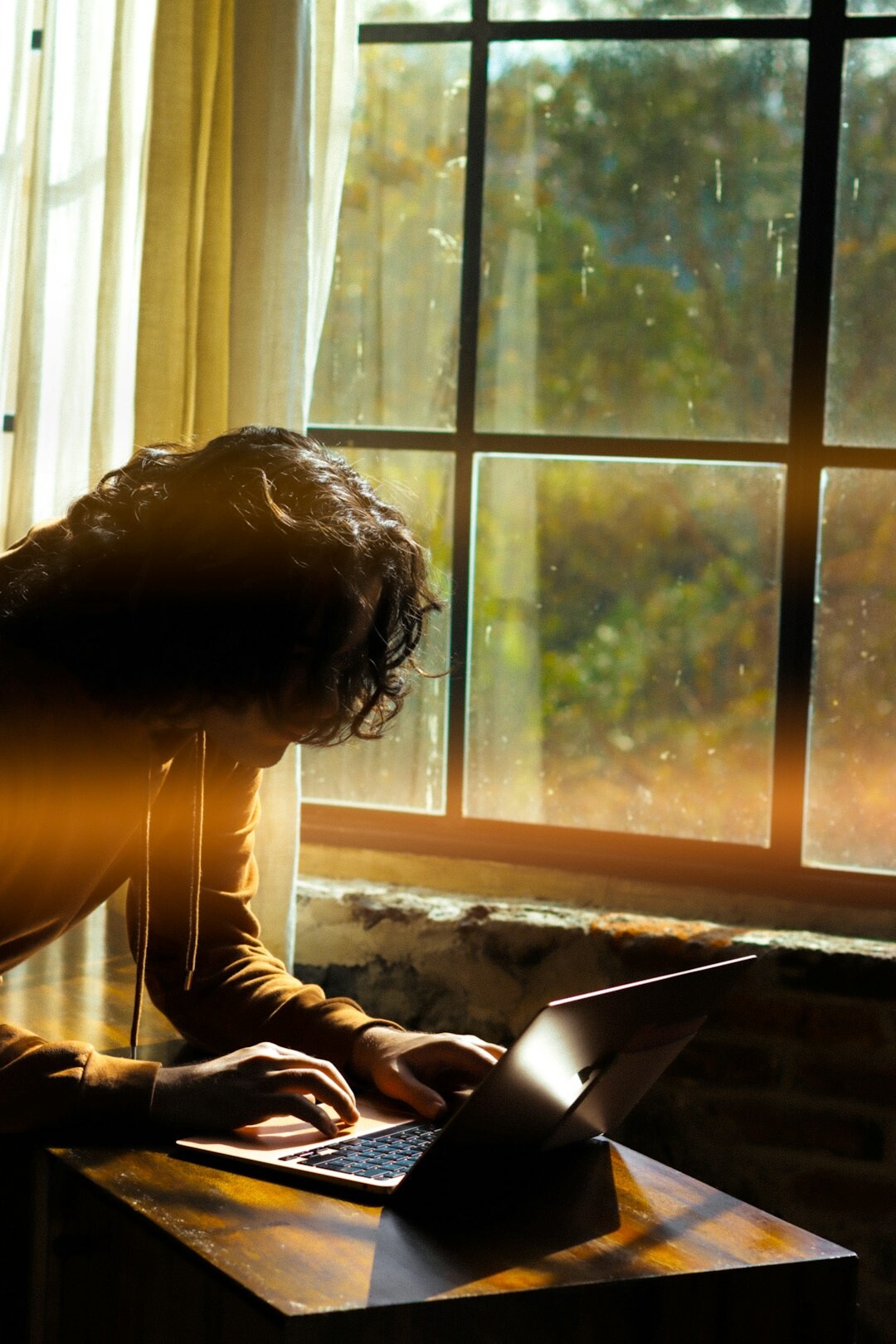 Woman writing thoughtfully in a journal at a sunlit desk