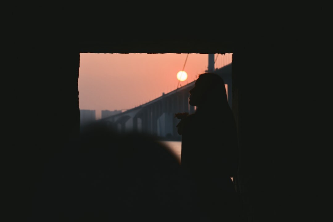 Silhouette of a person looking out a window at sunset